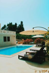 a pool with two lounge chairs and an umbrella at Villa na Mor' in Sutivan