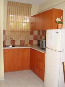 een keuken met houten kasten en een witte koelkast bij Cunucu Villas - Aruba Tropical Garden Apartments in Oranjestad