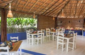 un restaurante con mesas y sillas blancas y una barra en Pousada Le Refuge, en Trancoso