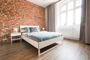 Un dormitorio con una pared de ladrillo y una cama en Apartament SweetDream en Katowice