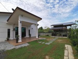 a white house with a porch and a yard at Orchard Villa Melaka in Malacca