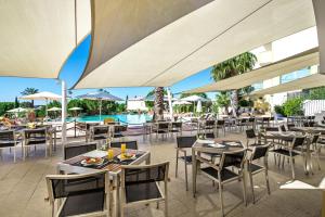 a restaurant with tables and chairs and a pool at Vale d'El Rei Hotel & Villas in Carvoeiro