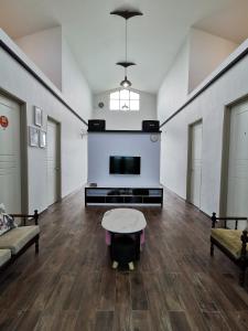 ein Wohnzimmer mit einem TV, einem Sofa und einem Tisch in der Unterkunft Orchard Villa Melaka in Malakka