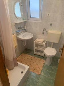 La salle de bains est pourvue de toilettes blanches et d'un lavabo. dans l'établissement Apartments Anna - peaceful and quiet, à Batalaži
