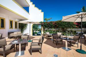 a patio with tables and chairs and umbrellas at Vale d'El Rei Hotel & Villas in Carvoeiro
