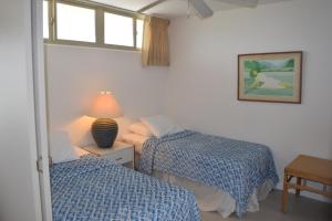 a bedroom with two beds and a lamp and a window at Hale Kai O'Kihei 305 in Kihei