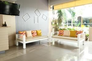 two white benches sitting in a room with a tv at Jomtien Plaza Residence in Jomtien Beach