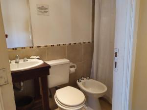 a bathroom with a white toilet and a sink at Hostería Costa Bonita in Villa Gesell
