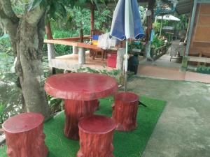 a table and three tree stools on the grass at ต้งโฮมหละปูน ณ ตูบคำ in Lamphun