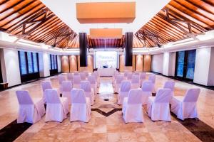 une salle de banquet avec des chaises blanches et une scène dans l'établissement Ramayana Candidasa, à Candidasa