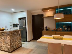 a kitchen with a table and a refrigerator at Apartamento Barra Bali in Barra de São Miguel