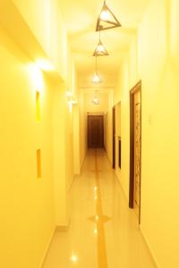 a hallway with yellow walls and a long hall with lights at Grand Suites Srirangam in Tiruchchirāppalli