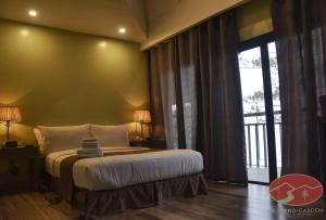 a bedroom with a bed and a large window at Skyland Garden Hotel and Resort in Baguio