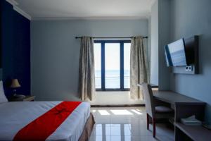 a bedroom with a bed and a desk and a window at RedDoorz Plus Syariah @ Hotel Boulevard Luwuk in Luwuk
