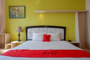 Un dormitorio con una cama con una almohada roja encima. en RedDoorz Plus Syariah @ Hotel Boulevard Luwuk, en Luwuk