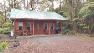 eine kleine rote Hütte mitten im Wald in der Unterkunft Alii Kane Cottages with Loft in Volcano