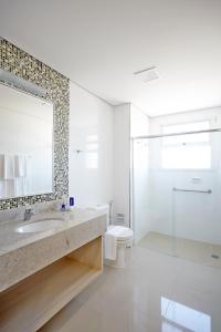 a bathroom with a sink and a toilet and a mirror at Porto Feliz Executive Hotel in Pôrto Feliz