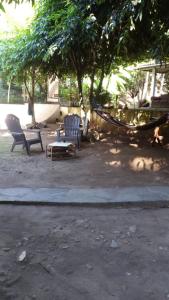 2 Stühle und eine Hängematte in einem Park in der Unterkunft Hostal El Balsamo in El Sunzal