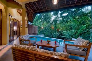 un patio con mesa, sillas y piscina en Samkhya Villas - CHSE Certified, en Ubud