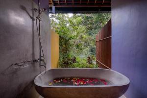 a large bath tub filled with flowers in a bathroom at Samkhya Villas - CHSE Certified in Ubud