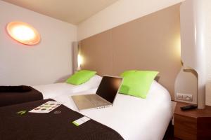 a hotel room with a laptop on a bed at Campanile Les Ulis - Courtaboeuf in Les Ulis