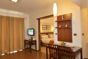 a room with a bed and a desk and a television at SFS Homebridge @ City in Trivandrum