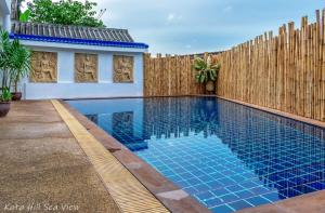 a swimming pool in a backyard with a wooden fence at Hotel Kata Hill Sea View in Kata Beach