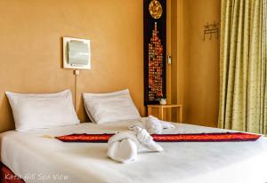 a bed with a stuffed animal laying on it at Hotel Kata Hill Sea View in Kata Beach
