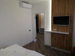 1 dormitorio con 1 cama y TV en la pared en Гостинний Двір, en Bar