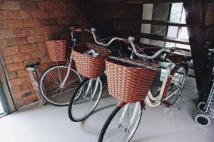 two bikes with baskets are parked next to a brick wall at ท่ามะโอบูทีคโฮมสเตย์ Tha Ma-O Bouteak Homestay in Lampang