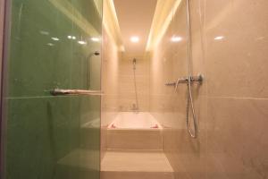 a bathroom with a shower and a bath tub at Pratunam Atrium Hotel in Bangkok