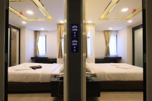two beds in a room with two mirrors at Pratunam Atrium Hotel in Bangkok