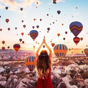 a woman standing in front of a bunch of hot air balloons at Nessa Cave Hotel in Goreme