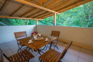 a wooden table and chairs on a porch with trees at Family Park Hotel Kyoshkove in Shumen