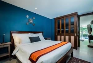 a bedroom with a large bed with blue walls at Kata Tranquil Villa - SHA Plus in Karon Beach