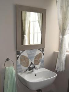 a bathroom with a sink and a mirror at Strandloper Apartments in Hermanus