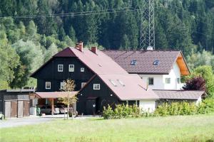 um grande celeiro preto e branco com uma casa em Tischlmühle Appartements & mehr em Gröbming