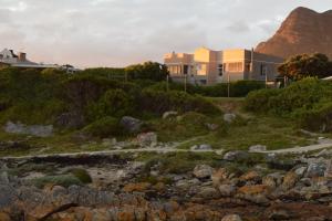 a house on a hill next to a mountain at Strandloper Apartments in Hermanus