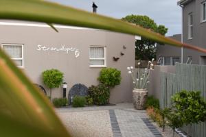 a white house with a fence and a yard at Strandloper Apartments in Hermanus