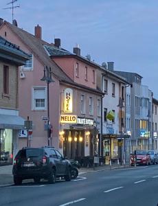 une voiture garée devant un magasin nello dans une rue de la ville dans l'établissement Hotel Nello, à Offenbach-sur-le-Main