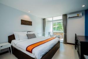 a bedroom with a bed and a desk and a window at Kata Tranquil Villa - SHA Plus in Karon Beach