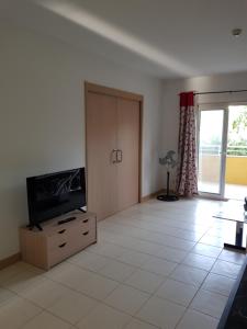 a living room with a flat screen tv on a cabinet at Surf Beach Vila Verde apartments in Santa Maria