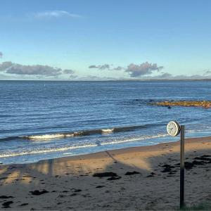 a clock on the beach next to the ocean at Vejby Strand Hotel in Vejbystrand