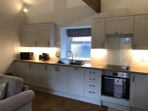 a kitchen with white cabinets and a counter top at The Milking Parlour, Wolds Way Holiday Cottages, 1 bed cottage in Cottingham