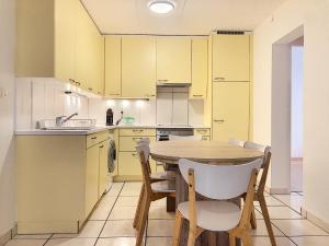 錫永的住宿－Apartment Del Sol Sion Center，厨房配有黄色橱柜和木桌及椅子