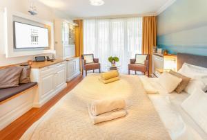 Großes Zimmer mit einem großen Bett und einem TV. in der Unterkunft Hotel Vier Jahreszeiten Binz - Adults Only in Binz