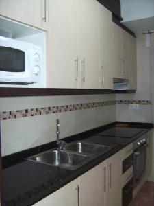 a kitchen with a sink and a microwave at Apartamento funcional y acogedor in L'Ametlla de Mar +10 photos