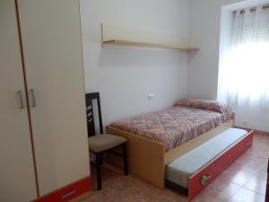 a small bedroom with a bed and a chair at Apartamento funcional y acogedor in L'Ametlla de Mar