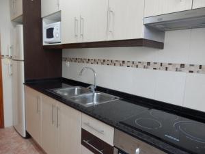 a kitchen with a sink and a microwave at Apartamento funcional y acogedor in L'Ametlla de Mar