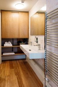 a bathroom with a white sink and wooden cabinets at The Rectory Rooms, Studio 1 in Skipton